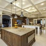 The kitchen has white cabinets combined with a darker island and serving bar.  The beams unify the different areas and provide strength to the design.  Limestone floors tie together all areas of the room.